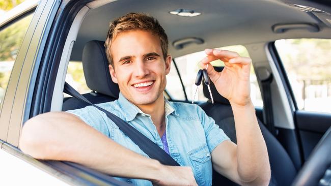 Portrait of happy young man showing new keys while sitting in car. Horizontal shot.