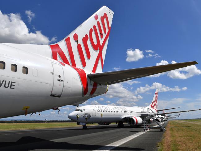 Grounded Virgin Australia aircraft are seen parked at Brisbane Airport in Brisbane, Tuesday, April 7, 2020. Brisbane Airport Corporation (BAC) is working with airlines by accommodating up to 100 grounded aircraft free of charge in response to government-mandated travel restrictions that have grounded a significant proportion of Australia's airline fleet because of the Coronavirus (COVID-19). (AAP Image/Darren England) NO ARCHIVING