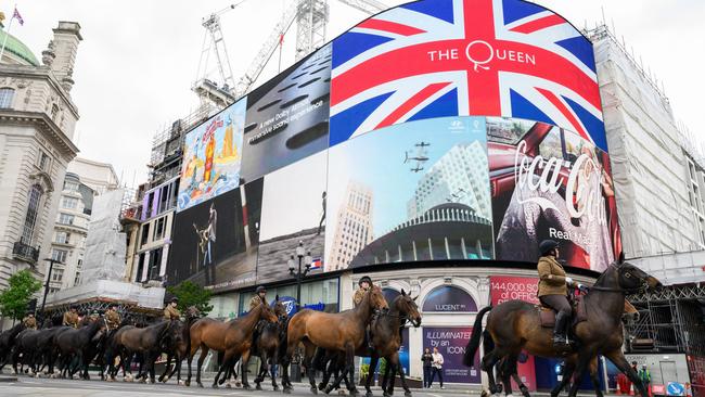 A message for Queen Elizabeth on the digital display as cavalry horses are walked through Piccadilly Circus. Picture: Getty Images.