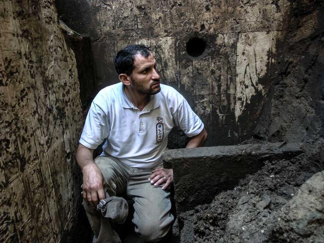 Out of the past ... An archaeologist sits amid the motifs — and muck — filling the memorial chapel found under homes in Abydos. Picture: Luxor Times.