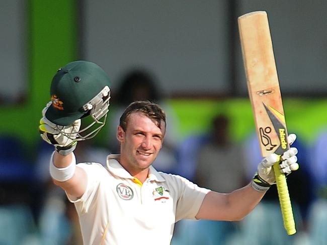 Former Australian batsman Phillip Hughes raises his bat and helmet in celebration after scoring a century against Sri Lanka. Picture: AFP