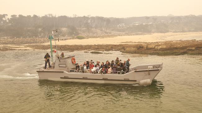 The first of the Mallacoota evacuees aboard a Navy landing boats, headed for the ships. Picture: David Caird