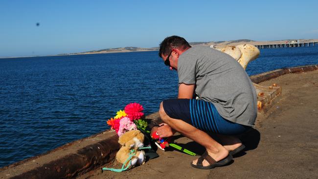 A man leaves flowers and toys at the Port Lincoln wharf in tribute. Picture: Ivon Perrin