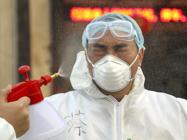 A worker in a protective suit is disinfected outside a hotel being used for people held in medical isolation in Wuhan. Picture: AP