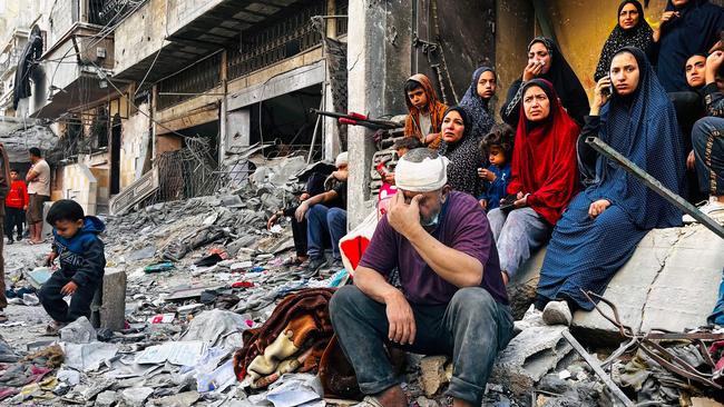 Stunned relatives wait for news of loved ones in the rubble of a building destroyed in an Israeli strike that killed at least 93 people, including many women and children. Picture: AFP