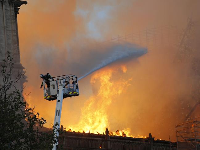 A fire fighter gestures as a hose as Notre Dame cathedral is burning in Paris, Monday, April 15, 2019. A catastrophic fire engulfed the upper reaches of Paris' soaring Notre Dame Cathedral as it was undergoing renovations Monday, threatening one of the greatest architectural treasures of the Western world as tourists and Parisians looked on aghast from the streets below. (AP Photo/Francois Mori)