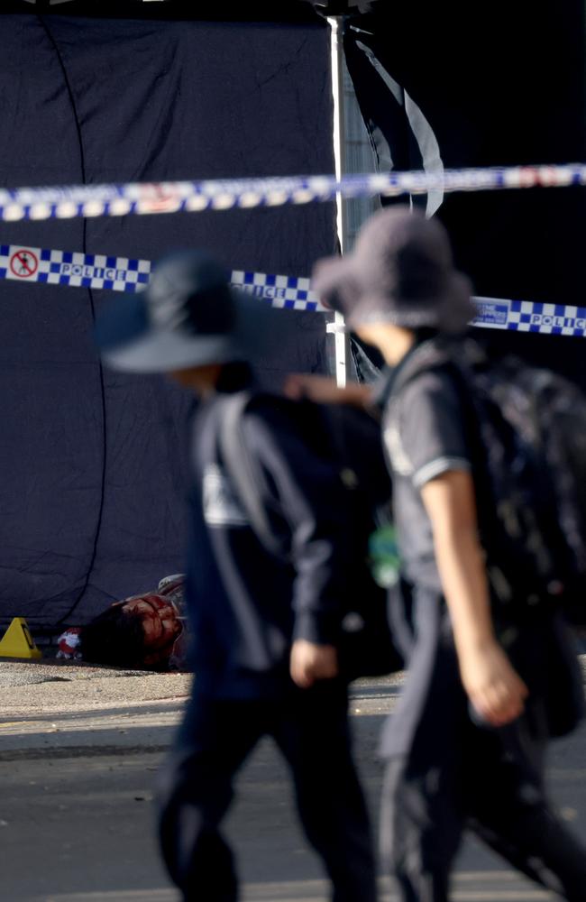 Schoolchildren walk past the bloody body of a man shot dead in Canterbury overnight. Forensic officers remained at the scene examining the body on Thursday morning. Picture: NCA NewsWire