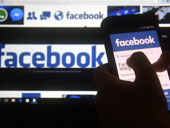 A cellphone and a computer screen display the logo of the social networking site Facebook on March 22, 2018, in Asuncion. Zuckerberg on March 22 failed to quell outrage over the hijacking of personal data from millions of people, as critics demanded the social media giant go much further to protect privacy. / AFP PHOTO / NORBERTO DUARTE