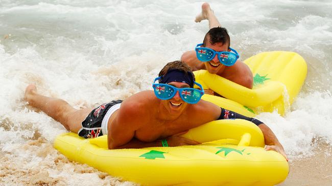 Beachgoers ride the surf on inflatable thongs. Picture: Getty Images