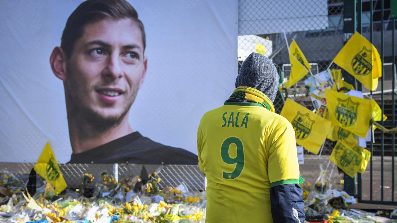 Supporters pay tribute and look at yellow flowers displayed in front of the portrait of Argentinian forward Emiliano Sala.