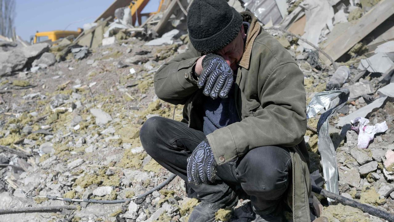 A man helps Ukrainian soldiers searching for bodies in the debris at the military school hit by Russian rockets. Picture: Bulent Kilic/AFP