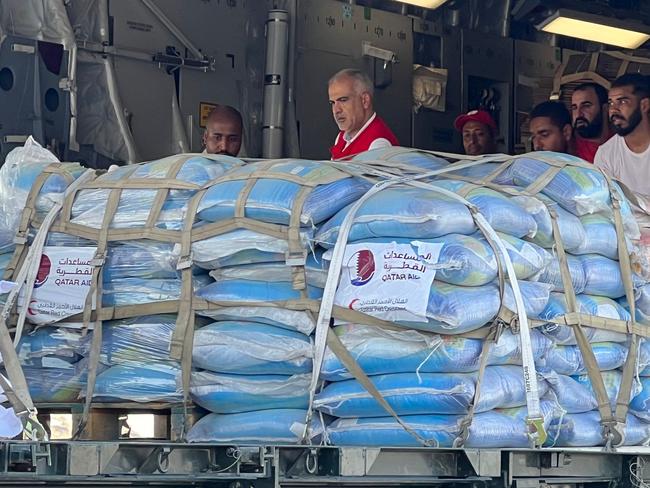 Volunteers from the Qatari and Egyptian Red Crescent humanitarian organisations unload aid destined for the Gaza Strip at el-Arish airport in Egyptâs northern Sinai peninsula on October 22, 2023, amid the ongoing battles between Israel and the Palestinian group Hamas. A 17-truck aid convoy entered Gaza from Egypt on October 22, as Israel intensified strikes on the Palestinian enclave facing a "catastrophic" humanitarian situation in the war sparked by Hamas's bloody attack. (Photo by Callum PATON / AFP)