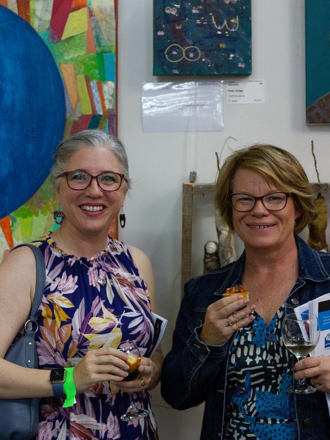 Samantha Ephraims poses in front of a work completed by her daughter, with her friend Perina McDonald.