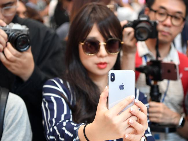 People take photos as a woman tests out a new iPhone X during a media event at Apple's new headquarters. Picture: AFP