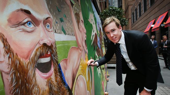 Tom Lynch signs his part of the mural unveiled in Melbourne on Tuesday. Picture: David Caird