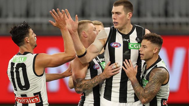 Mason Cox celebrates a goal with Scott Pendlebury and Jamie Elliott against the Eagles.