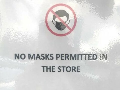 A "no masks permitted" sign displayed on the front door of Guitar Exchange in Morayfield.