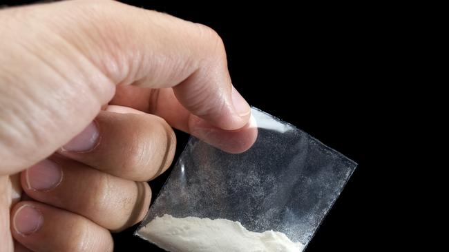 Generic photo of cocaine. Dealer is holding drug bag in his hand on a black background. Picture: iStock