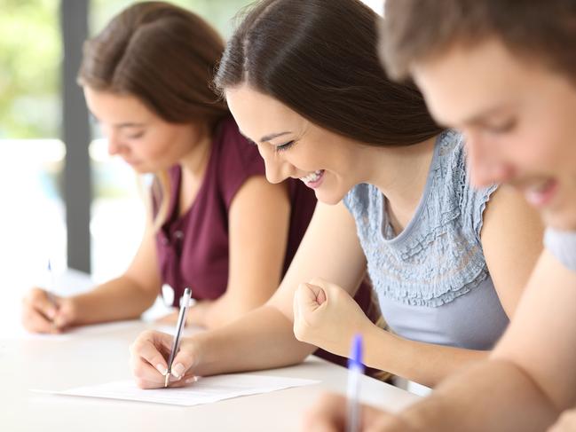 Excited student during an exam at classroom with other classmates in the background istock image