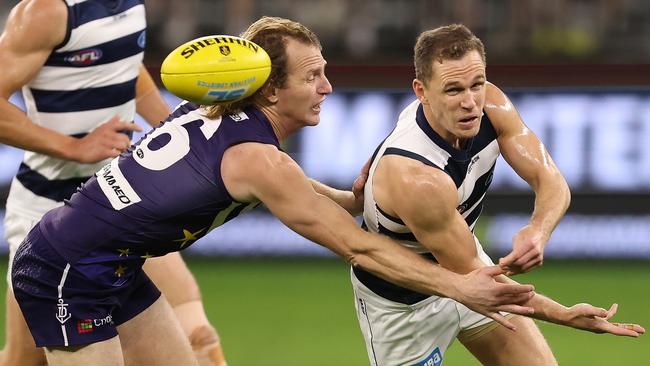 Joel Selwood fires off a handball despite pressure from David Mundy in Geelong’s Round 18 win over the Dockers at Perth Stadium on July 15, 2021. Picture: Getty Images