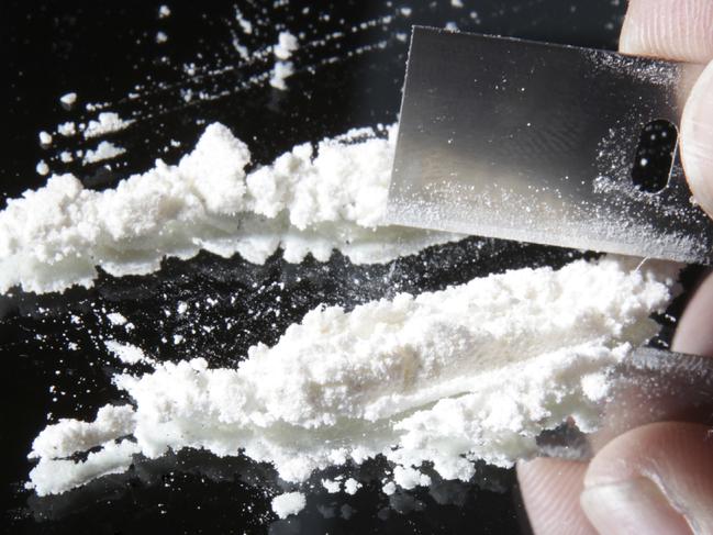 cocaine or other drugs cut with razor blade on mirror. hand dividing white powder narcotic