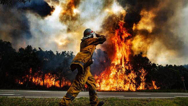 A rural firefighter watches on as a bushfire blazes east of the David Low Way at Peregian Beach. Picture: Lachie Millard