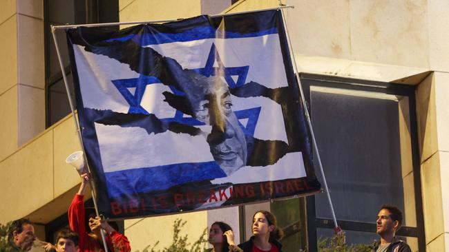 Israeli protesters lift a banner depicting Prime Minister Benjamin Netanyahu during a rally against the government's controversial judicial overhaul bill in Tel Aviv.