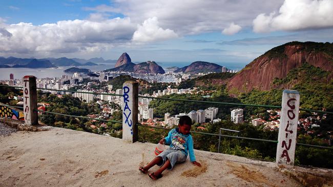 Daily life in the Favela's of Rio de Janeiro during the 2014 FIFA World Cup. A young local boy plays in the dirt on the top of favela Morro dos Prazeres with the most amazing view of Rio and Sugarloaf Mountain in the background.