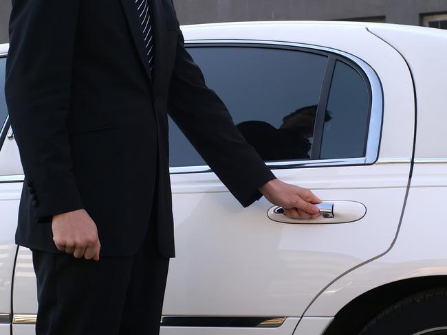 Limousine driver is opening car door for client.