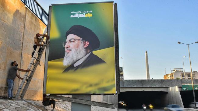 Workers hang billboards bearing a portrait of slain Lebanese Hezbollah Leader Hassan Nasrallah along the airport highway in Beirut. Picture: AFP