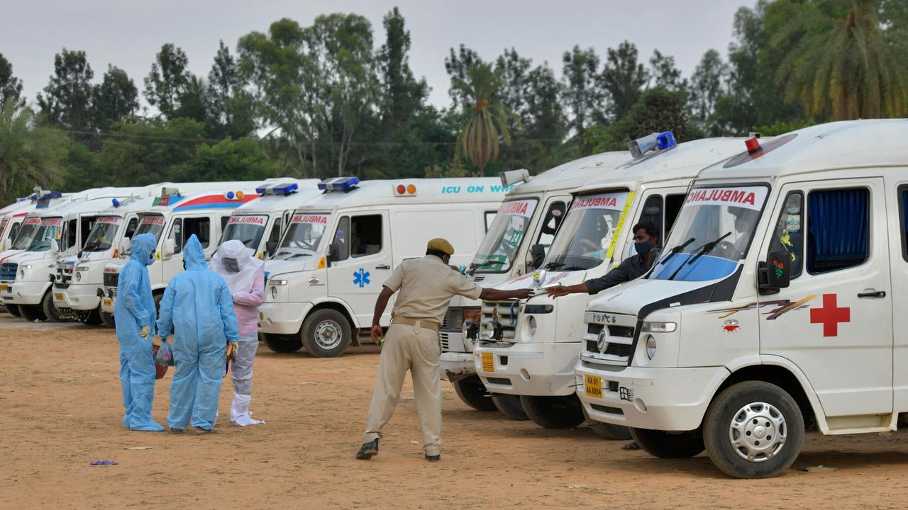 Relatives by ambulances carrying COVID-19 dead at open air crematorium outside Bangalore. Picture: Manjunath Kiran/AFP