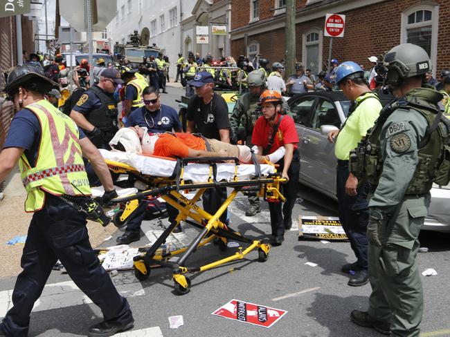 Rescue personnel help injured people after a car ran into a large group of protesters after a white nationalist rally. Picture: AP