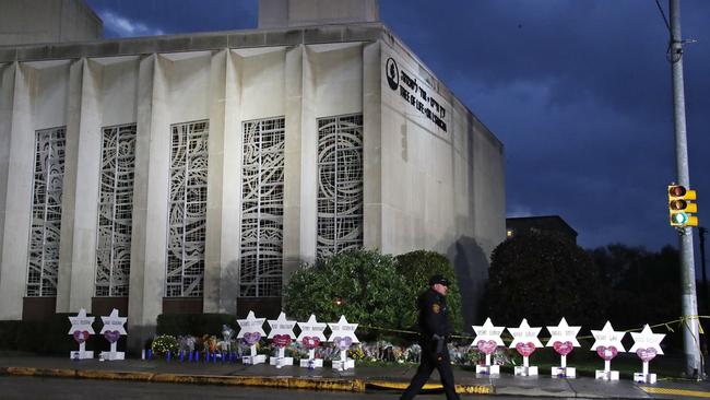 A Pittsburgh Police officer walks past the Tree of Life Synagogue and a memorial of flowers and stars. Picture; AP.