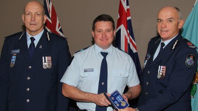 Senior Constable Brett Forte, centre, receives a service medal during his time at Caboolture Police Station.