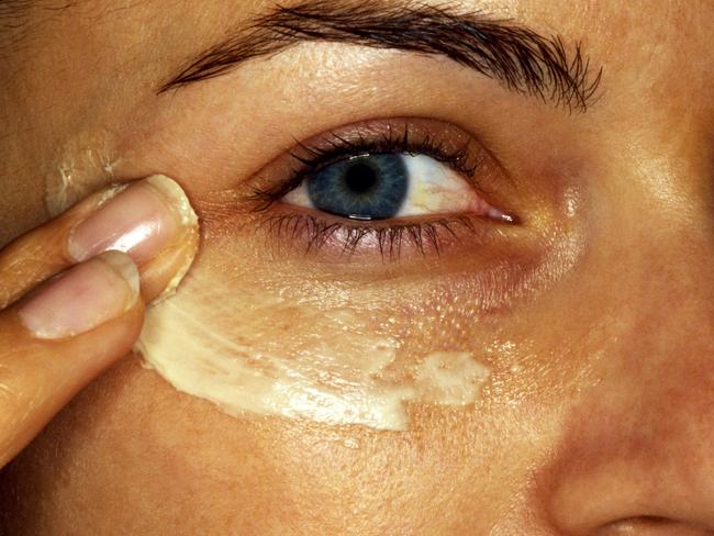 Woman applying cream under eye