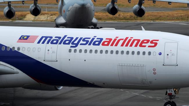 PERTH, AUSTRALIA - MARCH 25:  A Malaysia Airlines plane prepares to go out onto the runway and passes by a stationary Chinese Ilyushin 76 aircraft (top) at Perth International Airport on March 25, 2014 in Perth Australia.  The Australian Maritime Safety Authority has suspended the air and sea search for the missing Malaysian Airlines flight MH370 due to poor weather conditions in the search area. Search operations are expected to resume tomorrow.  (Photo by Greg Wood - Pool/Getty Images)