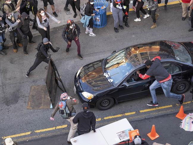 A man drives into the crowd at 11th and Pike, injuring at least one person, before exiting the car and brandishing a firearm in Seattle. Picture: Dean Rutz/The Seattle Times via AP