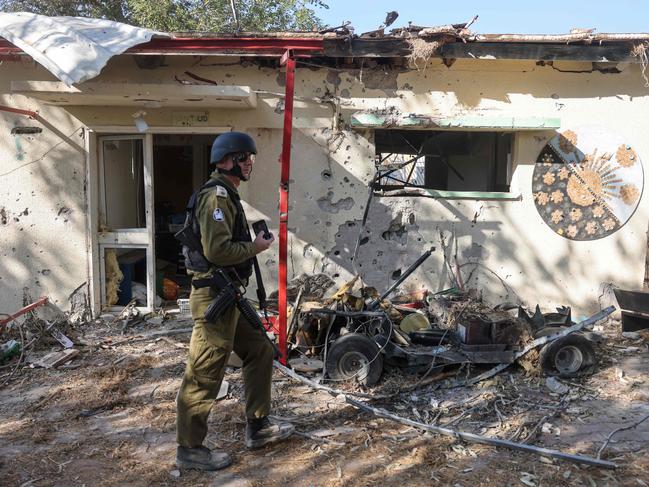 An Israeli soldier walks past burnt houses in Kibbutz Beeri near the border with Gaza. Picture: Menahem Kahana/AFP