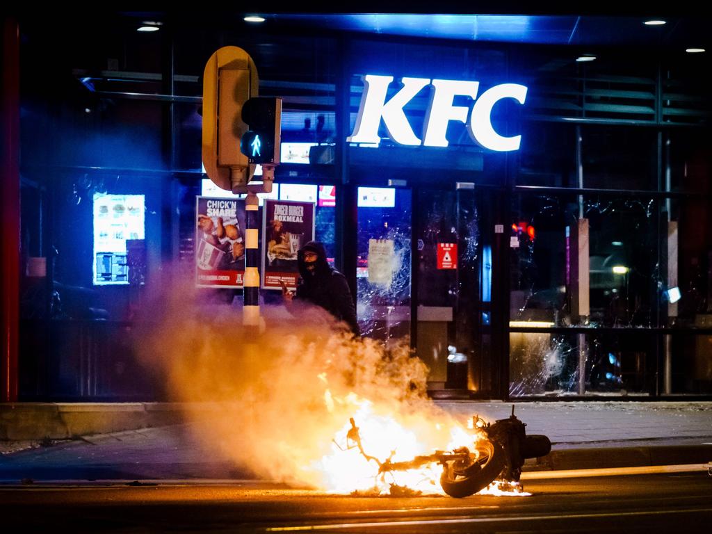 A motorbike is set on fire during protests over COVID-induced curfews in Holland. Picture: AFP