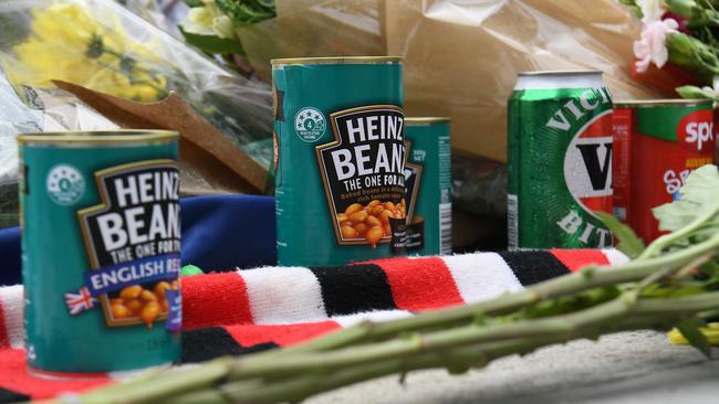 Cans of baked beans and beer at the base of Shane Warne’s statue outside the MCG on Sunday. Picture: AFP