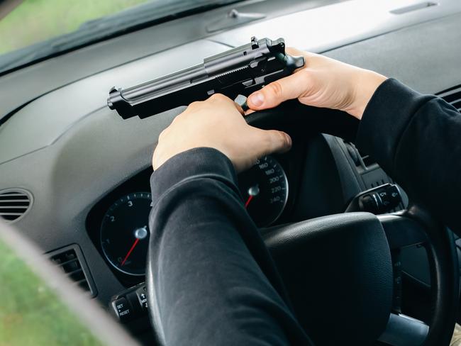 Theft of the car. Man with gun behind the wheel. Carjacking of vehicle. Robbing and crime.
