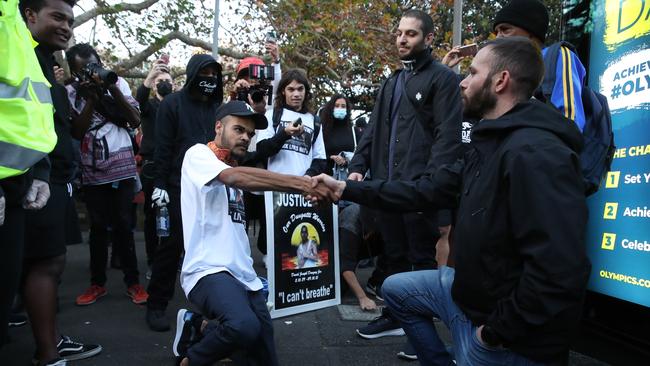 Paul Silva, left, takes a knee with a man he believes is an undercover police officer at a June protest. Picture: David Swift