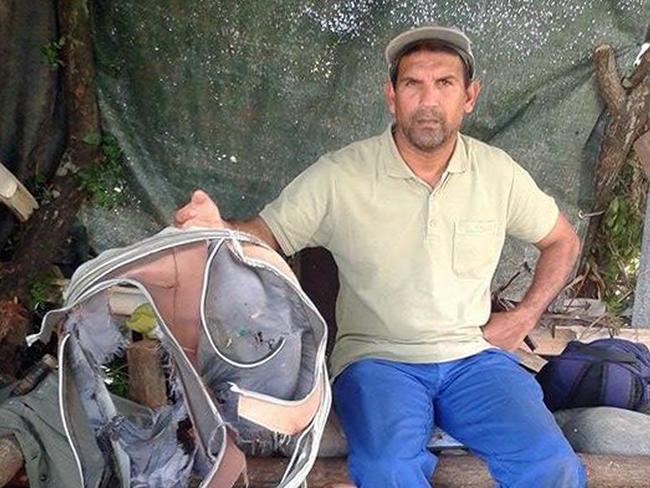 Johnny Begue with the recovered remains of a bag believed to be from flight MH370. Picture: AFP