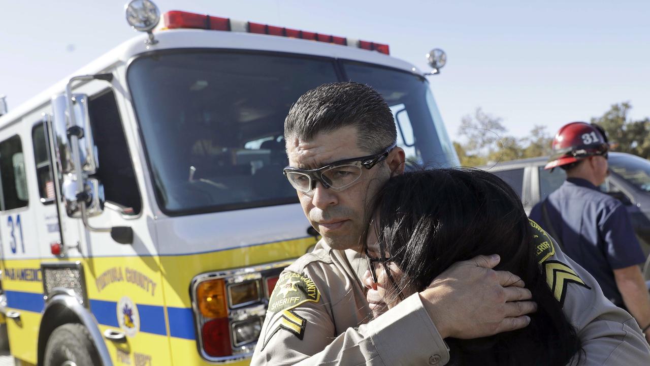 Los Angeles County Deputy Sheriff Armando Viera, centre, consoles an unidentified woman after a motorcade with the body of Sgt. Ron Helus went by. Picture: AFP