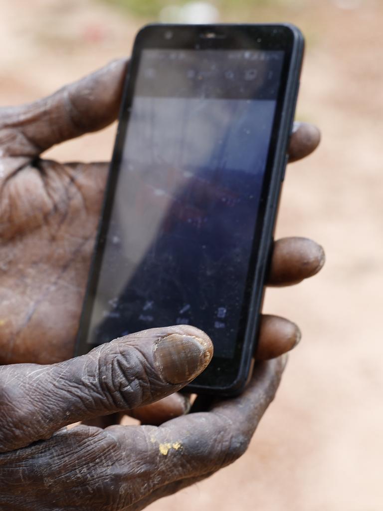 An Indigenous man checks his mobile phone in Aurukun, a small Indigenous town located on The Gulf of Carpentaria. Picture: Brendan Radke