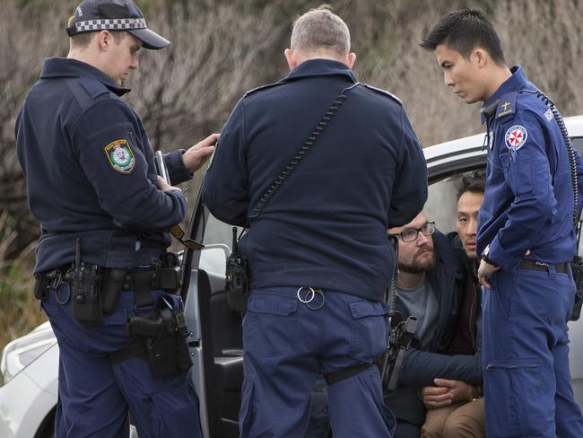 Police and an ambulance officer talk to two distraught men after the fatal fall. Picture: Damian Shaw