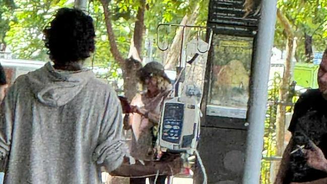 A Cairns Hospital patient hooked to a drip walks through the Cairns CBD.