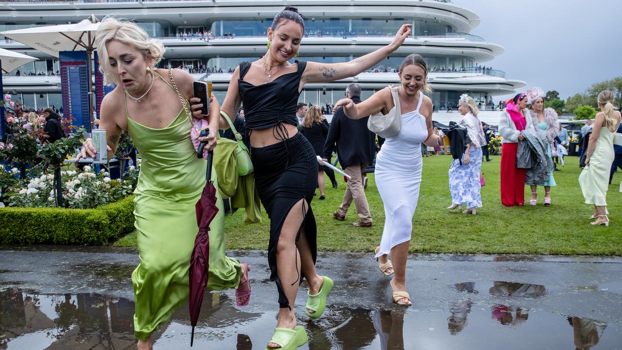 WATCH YOUR STEP: Revellers try to avoid puddles at Melbourne Cup at Flemington Racecourse. Picture: Jason Edwards