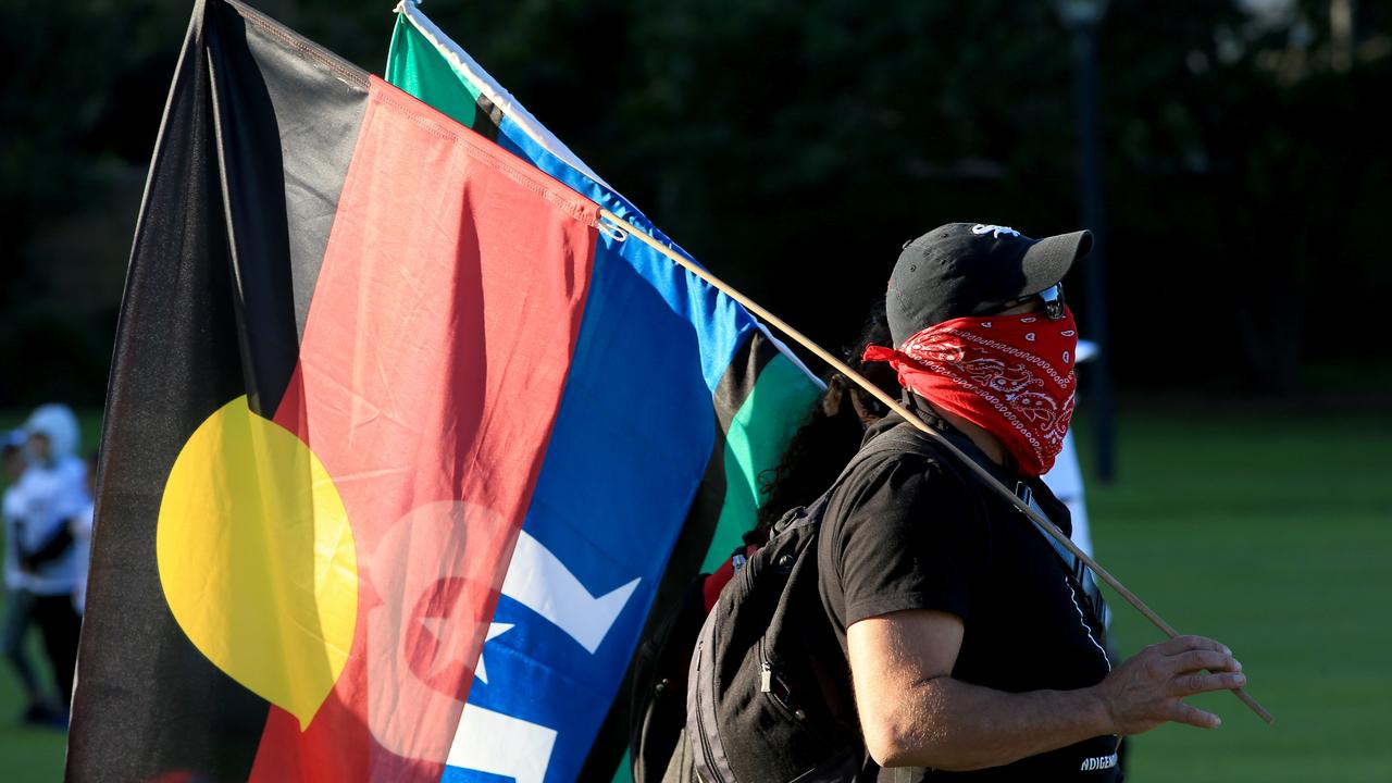 A protest attendee holding an Aboriginal flag and a Torres Strait Islander flag. Picture by Damian Shaw