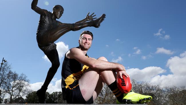 Glenelg's Liam McBean next to the Ken Farmer statue at Adelaide Oval. Picture: Tait Schmaal